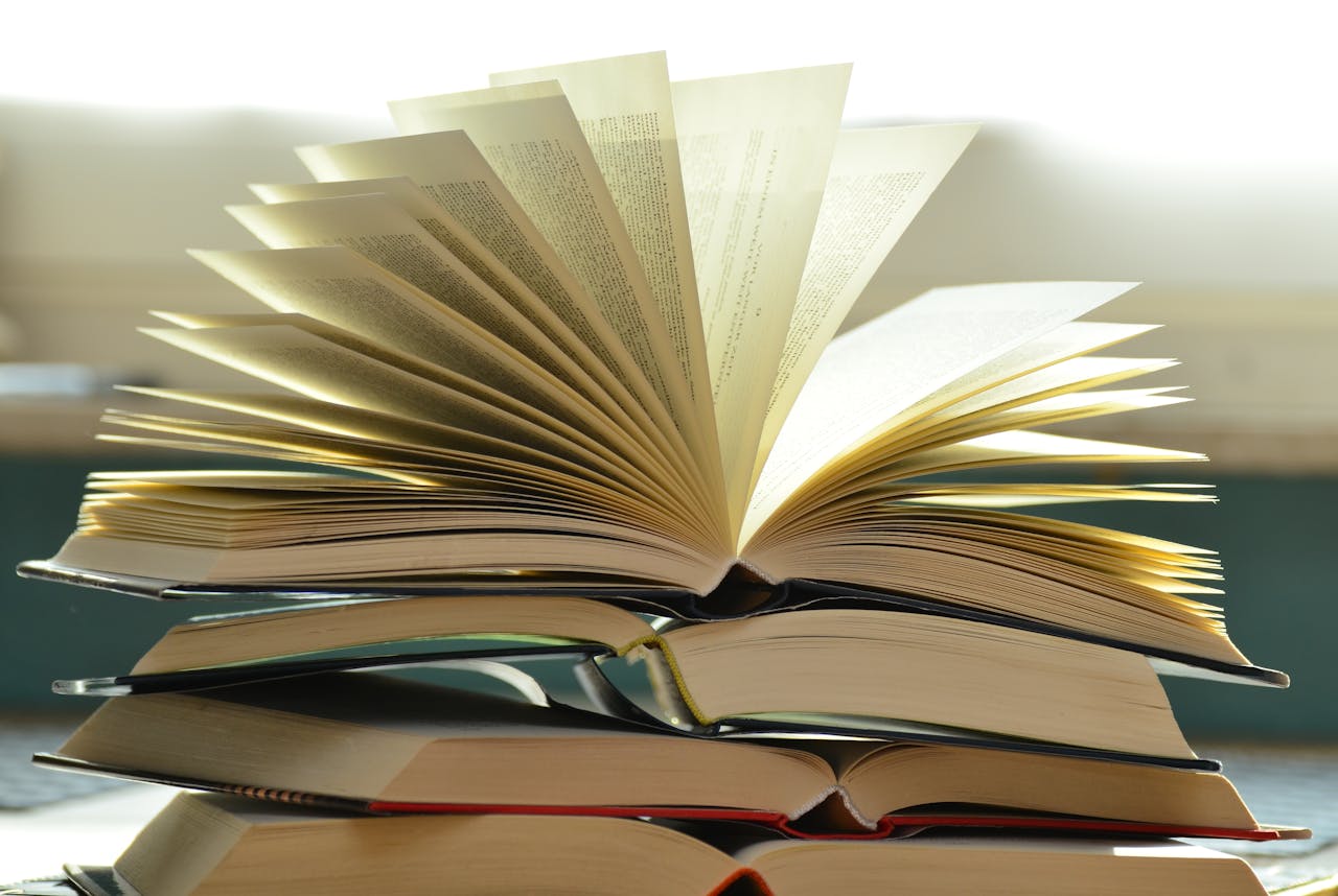 A close-up of a stack of open books with pages fanned out, capturing a study atmosphere.